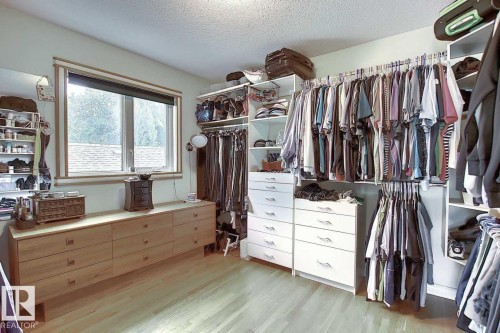 This dressing area features light wood flooring, a window with a blind, and extensive white built-in storage with hanging rails and drawers - 11126 52 Street, Edmonton, AB - Indoor With Storage