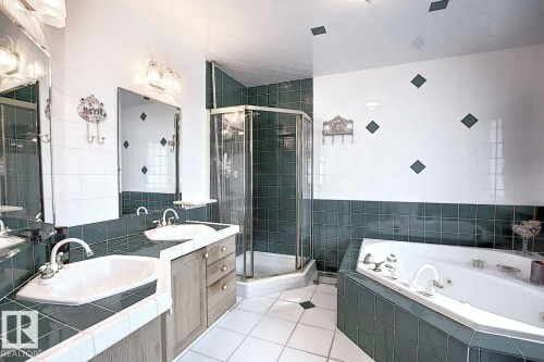 Bathroom featuring a double vanity with two sinks, a glass-enclosed shower, and a built-in jetted bathtub - 11126 52 Street, Edmonton, AB - Indoor Photo Showing Bathroom
