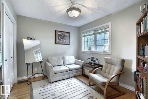 This room features hardwood floors, a window with horizontal blinds, and a built-in wooden bookshelf - 11126 52 Street, Edmonton, AB - Indoor Photo Showing Other Room