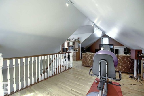 This expansive attic space features light hardwood flooring, a white railing, and track lighting - 11126 52 Street, Edmonton, AB - Indoor Photo Showing Other Room