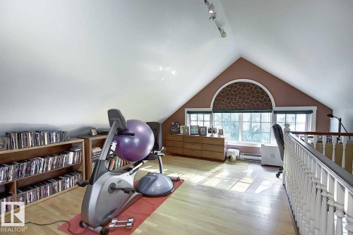 Versatile loft space featuring hardwood floors, track lighting, and a large arched window with patterned blinds - 11126 52 Street, Edmonton, AB - Indoor
