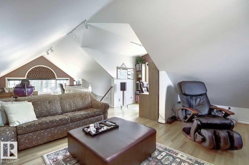 Spacious living area featuring sloped ceilings, track lighting, and light wood flooring - 11126 52 Street, Edmonton, AB - Indoor Photo Showing Living Room
