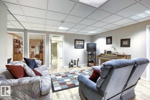 Spacious room with light wood flooring, white walls, and a tiled ceiling with integrated lighting - 11126 52 Street, Edmonton, AB - Indoor