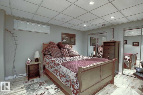 The room features light wood-style flooring and a drop ceiling with recessed lighting - 11126 52 Street, Edmonton, AB - Indoor Photo Showing Bedroom