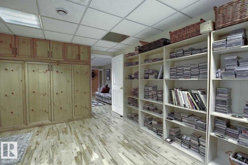 This versatile room features light-toned hardwood flooring, extensive built-in wooden cabinetry, and substantial shelving units providing ample storage - 11126 52 Street, Edmonton, AB - Indoor Photo Showing Other Room