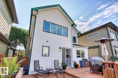The property features a spacious deck, white siding, and a gabled roof with dark green trim - 11126 52 Street, Edmonton, AB - Outdoor With Deck Patio Veranda With Exterior