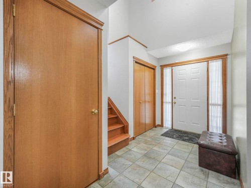 The entryway features tiled flooring, a white front door with sidelights, and a coat closet with wood doors - 11704 11 Avenue, Edmonton, AB - Indoor Photo Showing Other Room