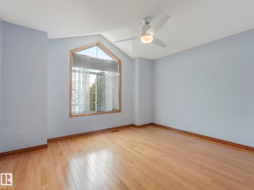 Room featuring hardwood floors, a vaulted ceiling, a ceiling fan with integrated lighting, and a large window with an arched top - 11704 11 Avenue, Edmonton, AB - Indoor Photo Showing Other Room