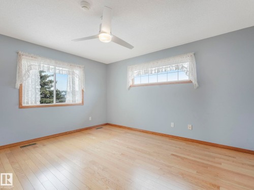 The room features light wood flooring, a ceiling fan with integrated lighting, and two windows allowing for natural light - 11704 11 Avenue, Edmonton, AB - Indoor Photo Showing Other Room
