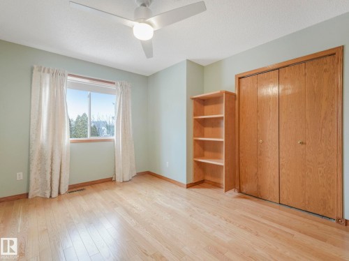 The property features hardwood floors, a window with natural light, a ceiling fan, and a built-in closet with bi-fold doors - 11704 11 Avenue, Edmonton, AB - Indoor Photo Showing Other Room