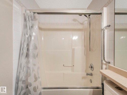 Bathroom with a shower and bathtub combination unit, featuring a clear shower curtain with a leaf pattern - 11704 11 Avenue, Edmonton, AB - Indoor Photo Showing Bathroom