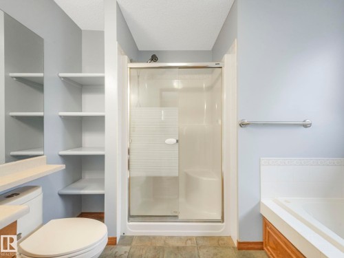 Bathroom featuring a shower with a sliding glass door, a toilet, built-in shelving, and a bathtub with a tiled surround - 11704 11 Avenue, Edmonton, AB - Indoor Photo Showing Bathroom