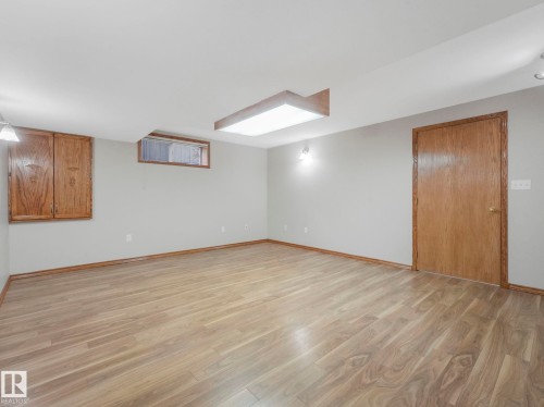 Spacious room featuring light-colored flooring, light-toned walls, and a wooden door with matching trim - 11704 11 Avenue, Edmonton, AB - Indoor Photo Showing Other Room