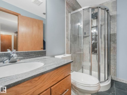 The bathroom features a glass-enclosed shower, a vanity with a granite countertop, and a white porcelain sink - 11704 11 Avenue, Edmonton, AB - Indoor Photo Showing Bathroom
