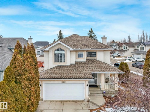 This property features a light-colored exterior, a shingled roof, and an attached garage with a white door - 11704 11 Avenue, Edmonton, AB - Outdoor With Facade