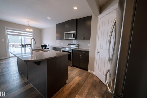 Kitchen featuring a large island with a sink, grey shaker-style cabinetry, and stainless steel appliances - 2132 52 St, Edmonton, AB - Indoor Photo Showing Kitchen With Double Sink