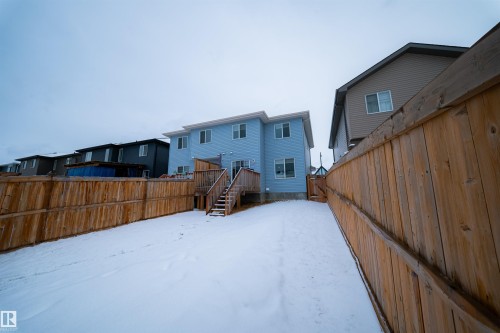 The property features a fenced backyard with a wooden deck and stairs, leading down to a snow-covered yard - 2132 52 St, Edmonton, AB - Outdoor With Exterior