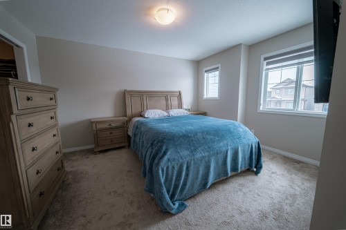 This room features neutral-toned walls, carpeting, and two windows providing natural light - 2132 52 St, Edmonton, AB - Indoor Photo Showing Bedroom