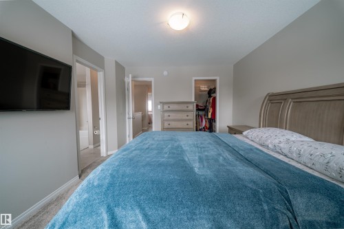 Bedroom featuring a neutral color palette, light-colored carpeting, and a built-in wall-mounted television - 2132 52 St, Edmonton, AB - Indoor Photo Showing Bedroom