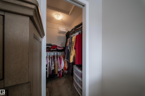 The property includes a closet with built-in shelving and hanging rods, illuminated by an overhead light fixture - 2132 52 St, Edmonton, AB - Indoor Photo Showing Other Room