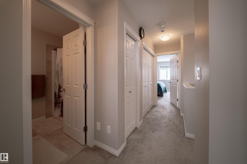 A hallway featuring light-colored carpeting, white baseboards, and overhead lighting - 2132 52 St, Edmonton, AB - Indoor Photo Showing Other Room