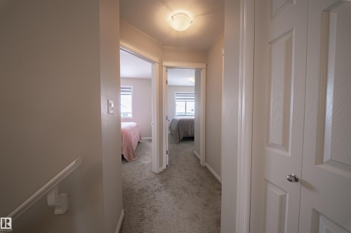 Hallway featuring carpeted flooring and light-colored walls, leading to rooms with windows - 2132 52 St, Edmonton, AB - Indoor Photo Showing Other Room