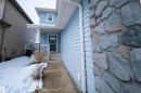 The property features light blue siding, a covered entrance with white railings, and a stone accent column - 2132 52 St, Edmonton, AB  - Outdoor 
