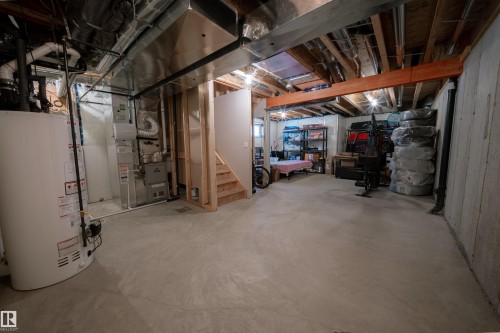 The property features a spacious unfinished basement with a water heater, furnace, and exposed wooden beams - 2132 52 St, Edmonton, AB - Indoor Photo Showing Basement