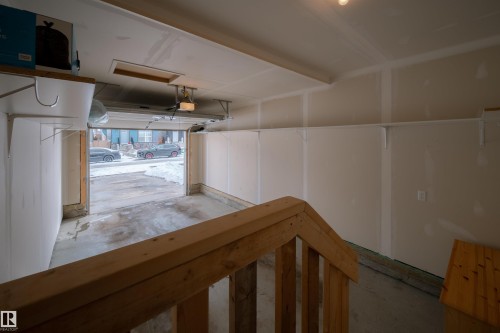 The property features a garage with a wooden handrail, open shelving for storage, and an automatic garage door opener - 2132 52 St, Edmonton, AB - Indoor