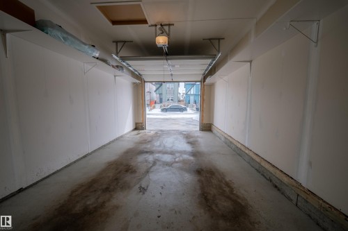 The garage features a concrete floor, white walls, and overhead shelving for storage - 2132 52 St, Edmonton, AB - Indoor Photo Showing Garage