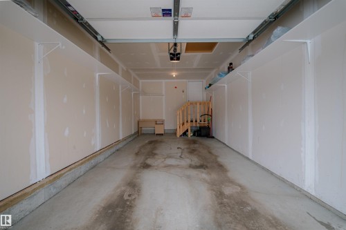 Spacious garage featuring a concrete floor, built-in shelving, and a wooden staircase - 2132 52 St, Edmonton, AB - Indoor Photo Showing Garage