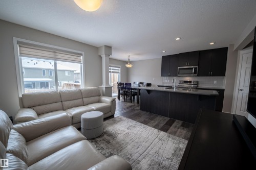 Open-concept living area featuring dark wood-style flooring, a large window with blinds, and recessed lighting - 2132 52 St, Edmonton, AB - Indoor Photo Showing Living Room
