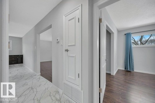 The property features a hallway with white marble-look tiled flooring and a dark wood cabinet - 12140 53 Street, Edmonton, AB - Indoor Photo Showing Other Room