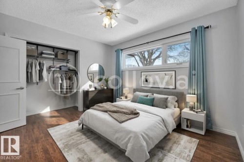 Bedroom featuring wood-finish flooring, a contemporary ceiling fan, and a built-in closet with shelving and hanging rods - 12140 53 Street, Edmonton, AB - Indoor Photo Showing Bedroom