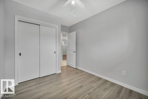 The room features light wood-style flooring, a ceiling fan, and a closet with sliding doors - 12140 53 Street, Edmonton, AB - Indoor Photo Showing Other Room