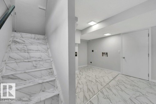 The property features a staircase with marble-patterned treads and risers, and a room with matching marble-patterned flooring - 12140 53 Street, Edmonton, AB - Indoor Photo Showing Other Room