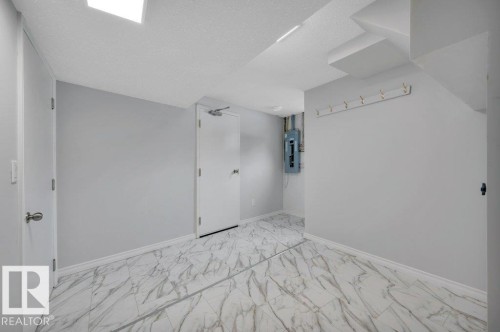This area of the property features light gray walls, white trim, and white and gray patterned flooring - 12140 53 Street, Edmonton, AB - Indoor Photo Showing Other Room