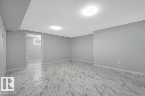 Spacious room featuring light gray walls, white baseboards, and patterned tile flooring - 12140 53 Street, Edmonton, AB - Indoor