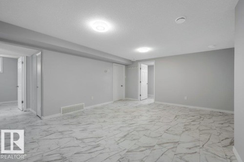 Expansive room featuring light gray walls, white trim, and light-colored marble-patterned floor tiles - 12140 53 Street, Edmonton, AB - Indoor Photo Showing Other Room
