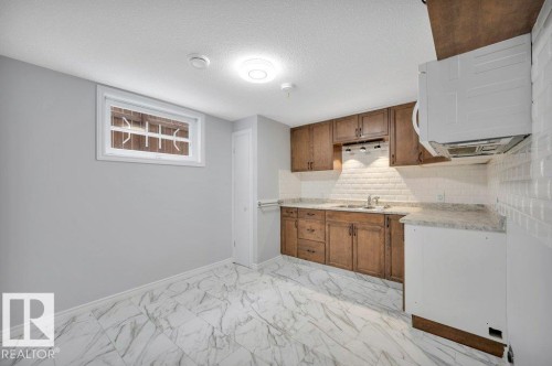 Kitchen with wood cabinetry, light-colored countertops, a white subway tile backsplash, and a wall-mounted microwave - 12140 53 Street, Edmonton, AB - Indoor Photo Showing Kitchen