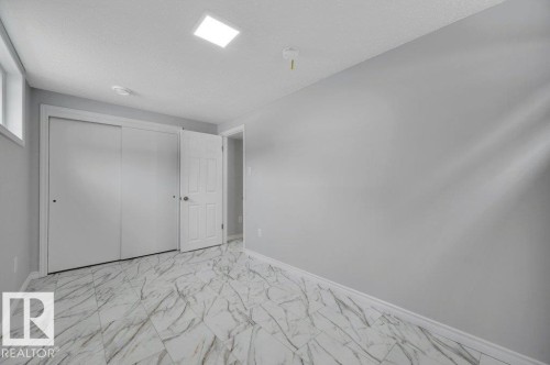 This room features a window, sliding closet doors, and patterned floor tiles - 12140 53 Street, Edmonton, AB - Indoor Photo Showing Other Room