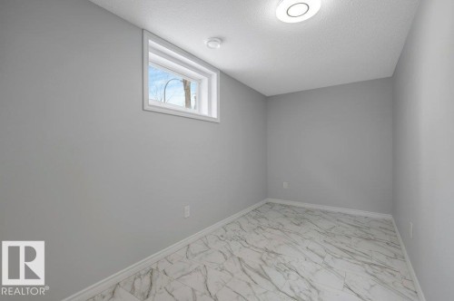 This room offers a clean, neutral palette with light gray walls and a complementary white baseboard - 12140 53 Street, Edmonton, AB - Indoor Photo Showing Other Room