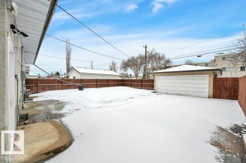 The property features a detached garage with a white garage door, a wooden fence, and a paved driveway - 12140 53 Street, Edmonton, AB - Outdoor