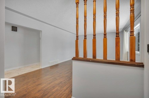 Entryway featuring hardwood flooring, a wooden banister, and light grey walls - 12140 53 Street, Edmonton, AB - Indoor Photo Showing Other Room