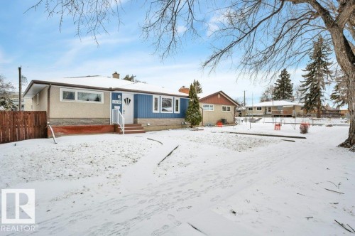 The property features a ranch-style exterior with blue siding and a well-maintained front yard - 12140 53 Street, Edmonton, AB - Outdoor