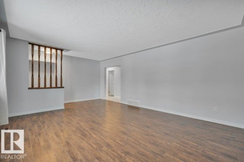 This spacious area features wood-look flooring and light grey walls, offering a versatile backdrop - 12140 53 Street, Edmonton, AB - Indoor Photo Showing Other Room