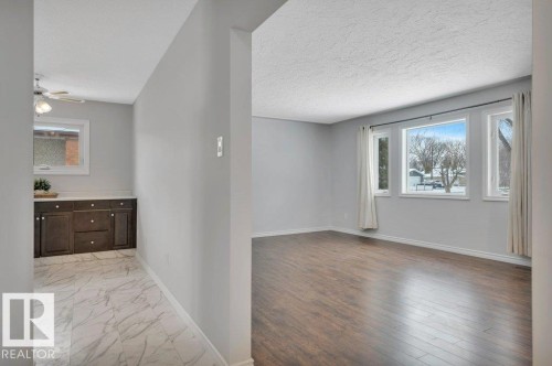 This property features durable wood flooring and large windows providing ample natural light - 12140 53 Street, Edmonton, AB - Indoor Photo Showing Other Room