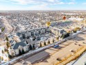 Aerial view of the property and its surrounding area, featuring a multi-story building with balconies, a paved parking lot, and nearby residential streets - 217 160 Magrath Road, Edmonton, AB  - Outdoor With View 