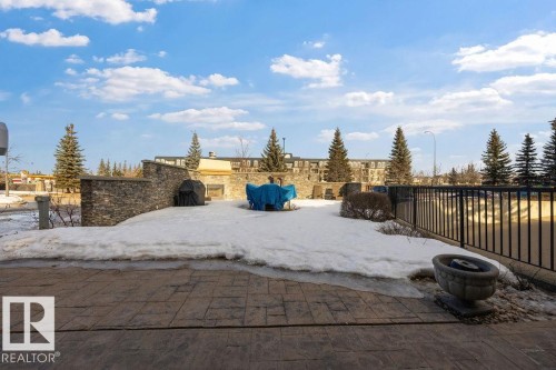 Expansive outdoor patio area featuring patterned paving, a stone privacy wall and gas BBQ - 217 160 Magrath Road, Edmonton, AB - Outdoor With View