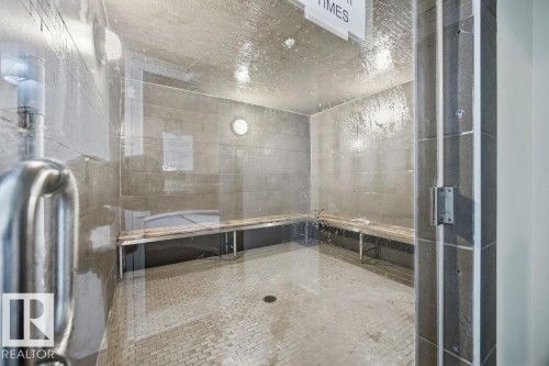 The property features a steam room with tiled walls and flooring, equipped with built-in wooden benches for comfort - 217 160 Magrath Road, Edmonton, AB - Indoor Photo Showing Bathroom